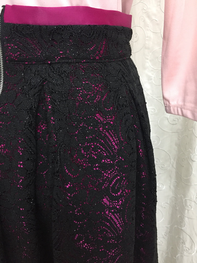 Čierna čipkovaná spoločenská sukňa podšívaná ciklamenovým saténom a spodničkou s tylom. Zapínanie na zips na zadnom diely.  Veľkosť: 38  Zloženie: Polyester 95% Elastan 5%